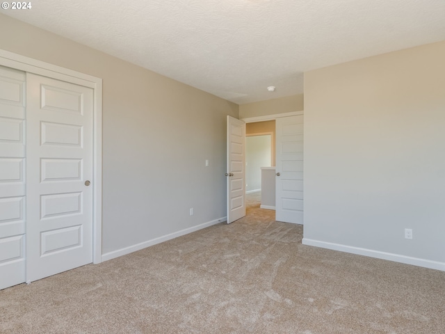 spare room featuring light carpet and a textured ceiling