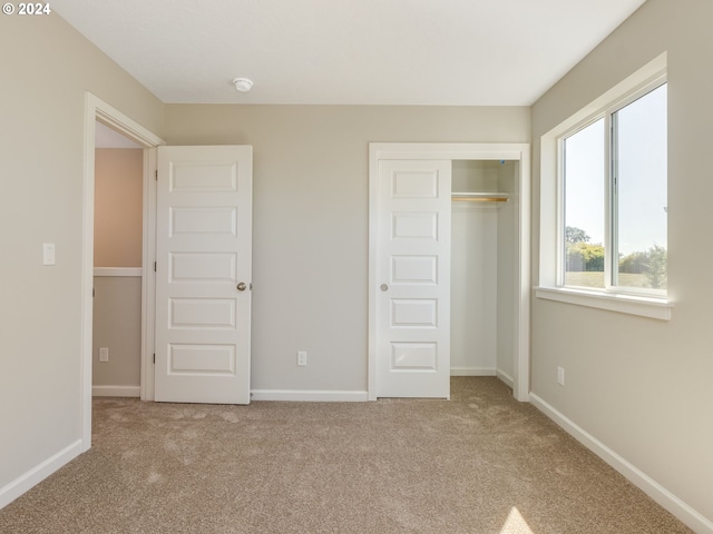 unfurnished bedroom featuring light colored carpet and a closet