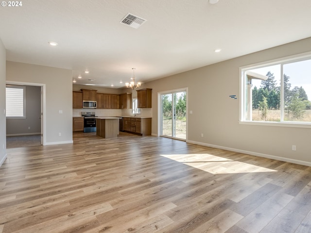 unfurnished living room featuring a notable chandelier, light hardwood / wood-style floors, and sink