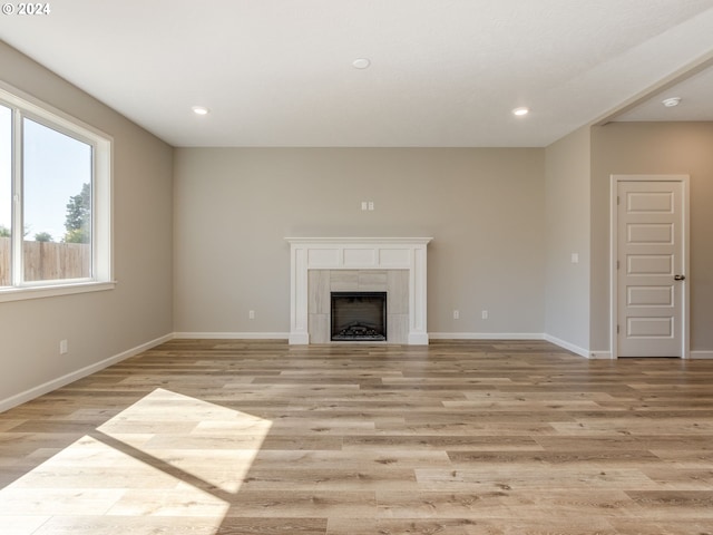 unfurnished living room with light hardwood / wood-style flooring and a tile fireplace