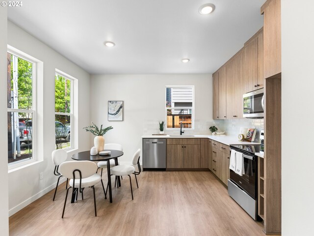 3550 NE Garfield Ave Unit 1, Portland, OR 97212 - kitchen with backsplash, sink, light hardwood / wood-style flooring, and stainless steel appliances