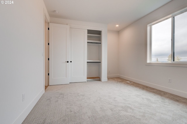 unfurnished bedroom with light carpet and a closet