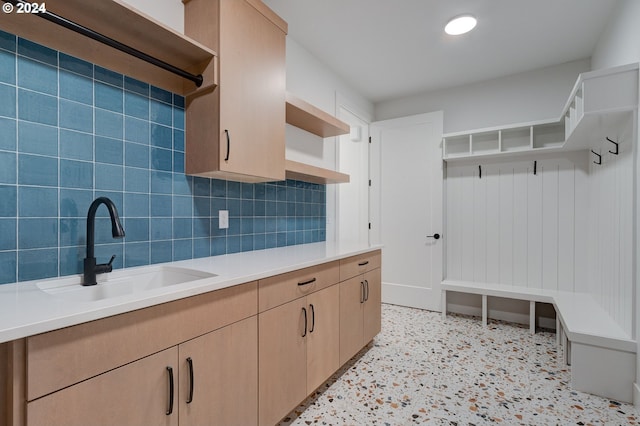 kitchen with open shelves, a sink, decorative backsplash, light countertops, and light speckled floor