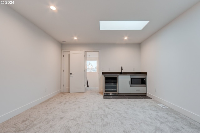 interior space with white cabinetry, carpet floors, stainless steel microwave, and beverage cooler