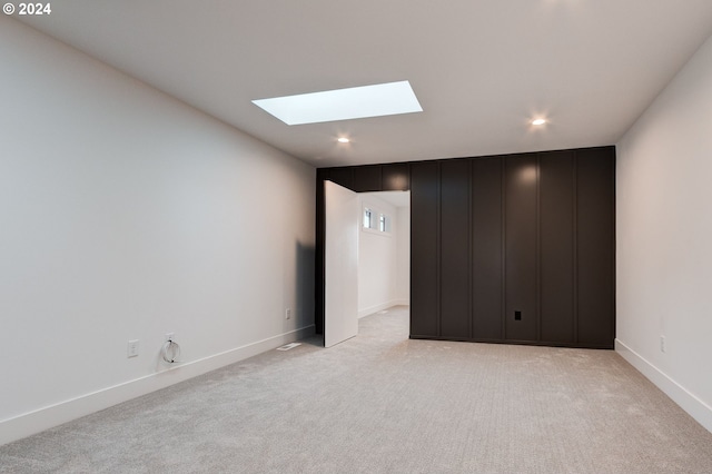 spare room featuring recessed lighting, light colored carpet, a skylight, and baseboards