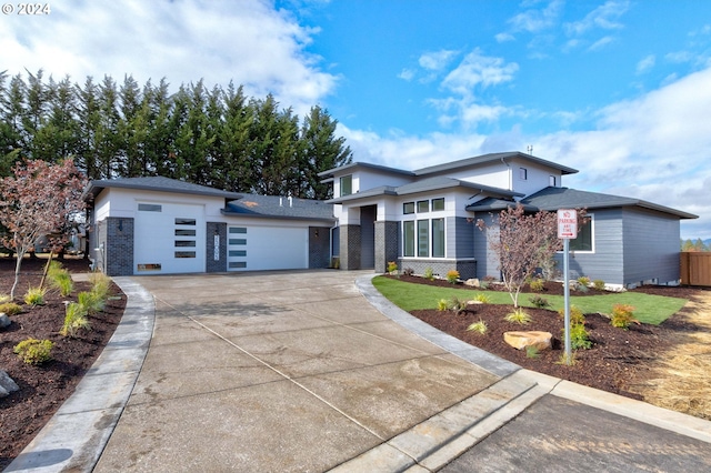 prairie-style house with brick siding, concrete driveway, and a garage