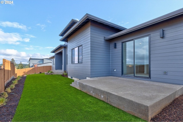 rear view of property with a patio area, a lawn, and fence