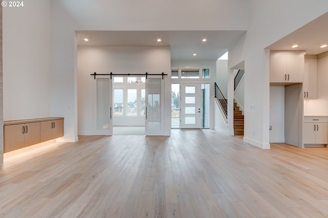 unfurnished living room with light hardwood / wood-style flooring and a barn door