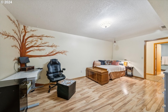 bedroom with light hardwood / wood-style floors and a textured ceiling