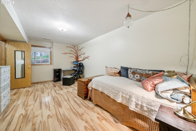 bedroom with light hardwood / wood-style flooring and a textured ceiling