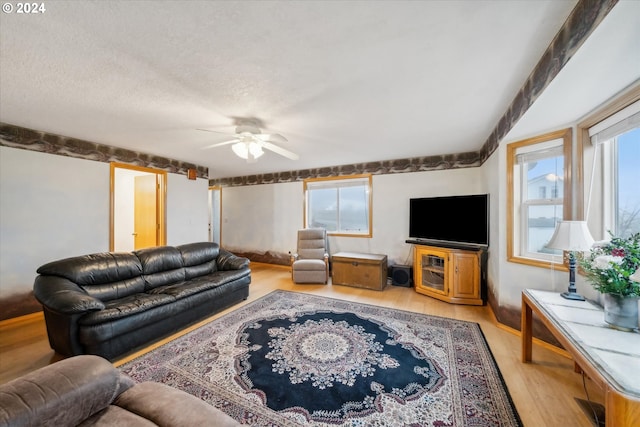 living room featuring a textured ceiling, light wood-type flooring, and ceiling fan