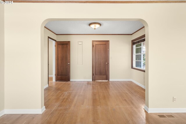 interior space featuring a textured ceiling, light hardwood / wood-style floors, and ornamental molding