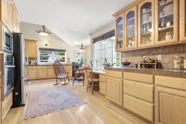 kitchen with appliances with stainless steel finishes, tasteful backsplash, vaulted ceiling, light brown cabinets, and light hardwood / wood-style floors