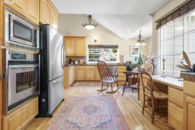 kitchen featuring light brown cabinets, stainless steel appliances, lofted ceiling, and light wood-type flooring