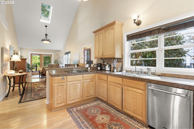 kitchen featuring a skylight, high vaulted ceiling, stainless steel dishwasher, light brown cabinetry, and light wood-type flooring