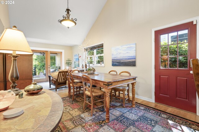 dining room with french doors, light wood-type flooring, high vaulted ceiling, and plenty of natural light