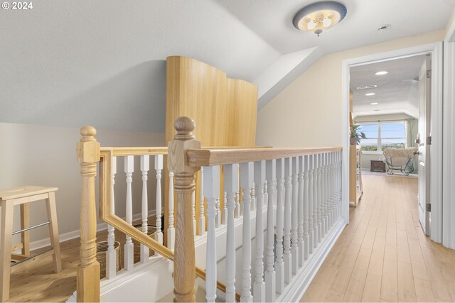 hall featuring light hardwood / wood-style floors and lofted ceiling