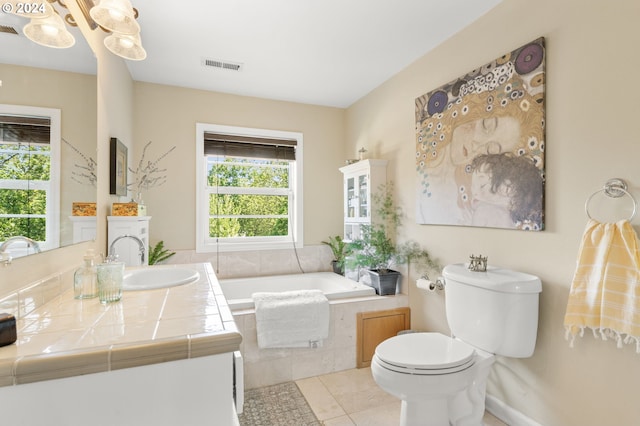 bathroom with toilet, vanity, tile patterned floors, and tiled tub