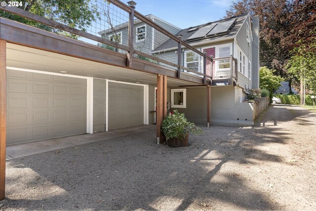 view of side of property with solar panels, a balcony, and a garage