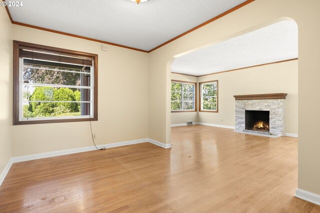 unfurnished living room featuring a fireplace, light hardwood / wood-style flooring, a textured ceiling, and ornamental molding