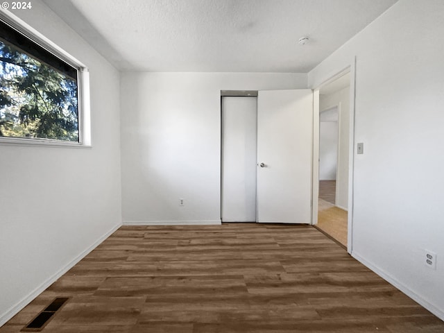 unfurnished bedroom with a closet, a textured ceiling, and dark wood-type flooring