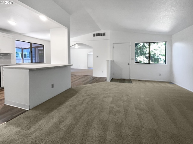 unfurnished living room featuring dark wood-type flooring, vaulted ceiling, and a wealth of natural light