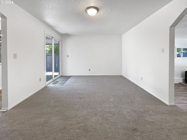 spare room featuring a textured ceiling and dark colored carpet