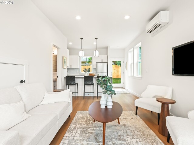 living room with light wood-type flooring and an AC wall unit