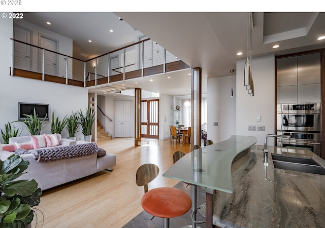 living room with light hardwood / wood-style floors, a towering ceiling, and sink