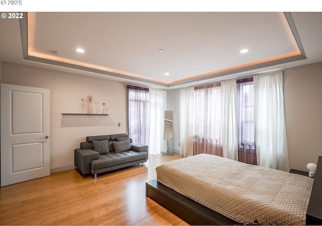 bedroom with a raised ceiling and light hardwood / wood-style flooring