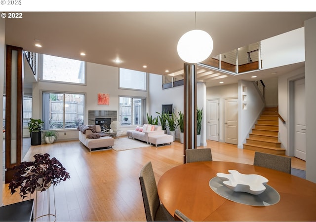 dining space with light hardwood / wood-style flooring, a high ceiling, and a tiled fireplace