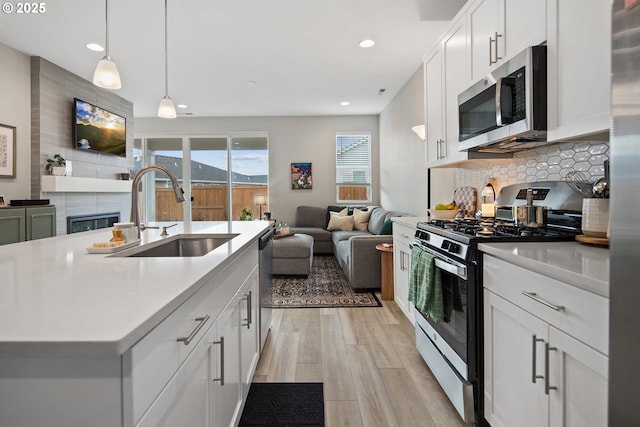 kitchen with pendant lighting, sink, an island with sink, white cabinetry, and stainless steel appliances