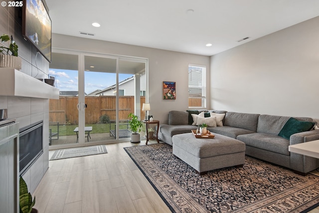 living room featuring a tiled fireplace and hardwood / wood-style flooring