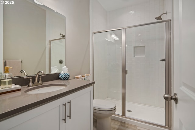 bathroom featuring vanity, toilet, and a shower with shower door