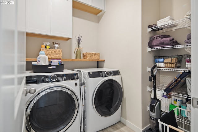 laundry area with washer and dryer, light hardwood / wood-style floors, and cabinets