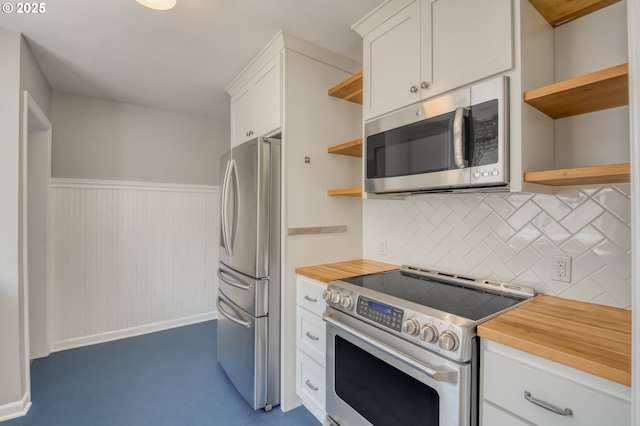 kitchen with stainless steel appliances, open shelves, white cabinetry, butcher block counters, and decorative backsplash