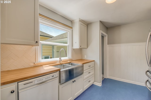kitchen with wooden counters, dishwasher, a sink, tasteful backsplash, and white cabinetry