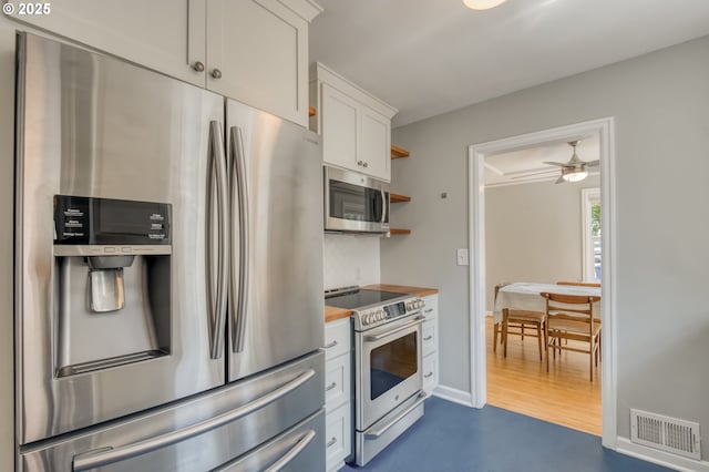 kitchen featuring stainless steel appliances, backsplash, white cabinetry, butcher block countertops, and open shelves