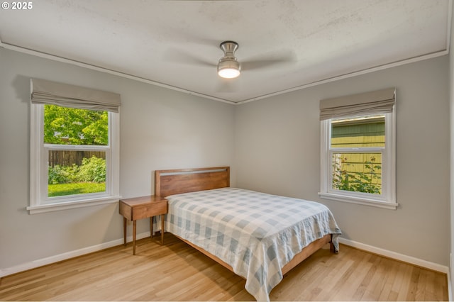 bedroom with light wood-style flooring, baseboards, ornamental molding, and ceiling fan