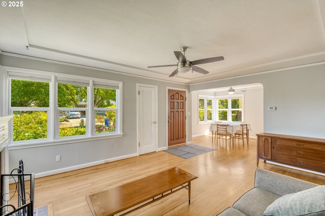 living area featuring a ceiling fan, wood finished floors, baseboards, and ornamental molding