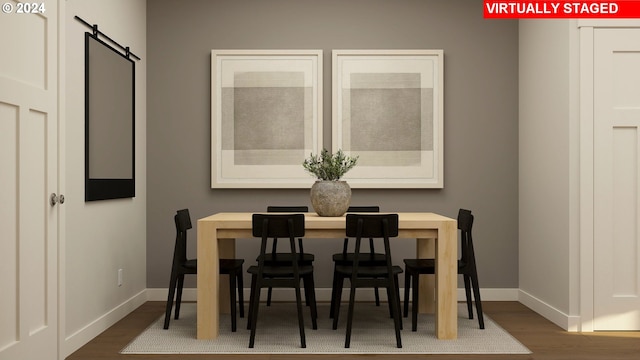 dining space with dark wood-type flooring and a barn door