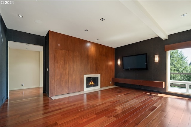 unfurnished living room with beamed ceiling, hardwood / wood-style flooring, and a fireplace