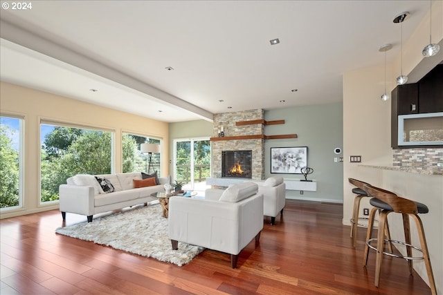 living room featuring a stone fireplace and dark wood-type flooring