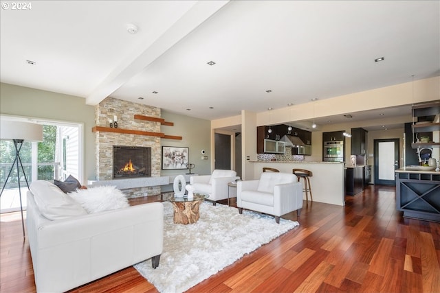 living room featuring a fireplace, beam ceiling, dark hardwood / wood-style flooring, and sink