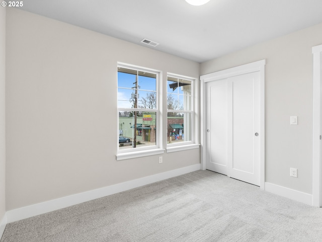 unfurnished bedroom featuring light colored carpet and a closet