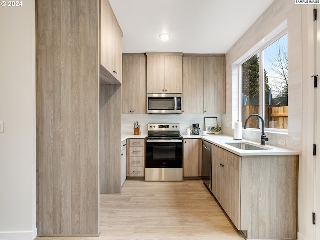 kitchen featuring light hardwood / wood-style floors, sink, backsplash, and stainless steel appliances