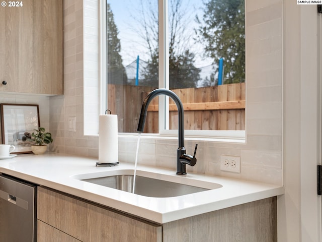 kitchen featuring plenty of natural light, sink, tasteful backsplash, and stainless steel dishwasher