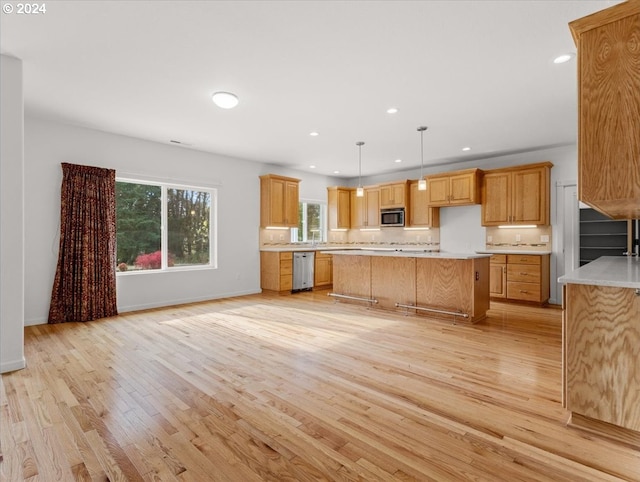 kitchen with light hardwood / wood-style flooring, stainless steel appliances, a center island, and pendant lighting