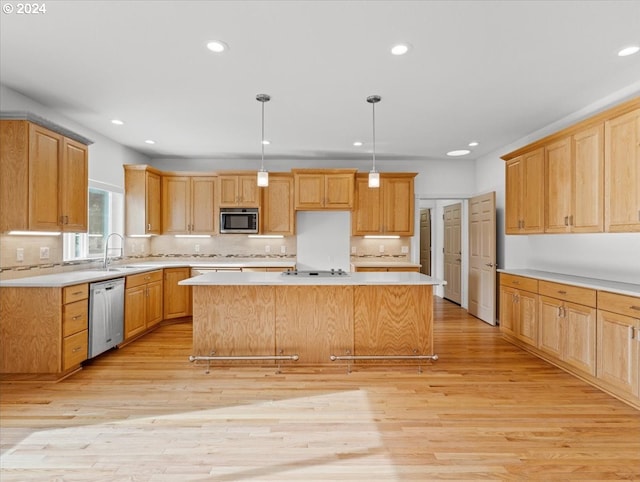 kitchen with a center island, appliances with stainless steel finishes, pendant lighting, and light hardwood / wood-style floors