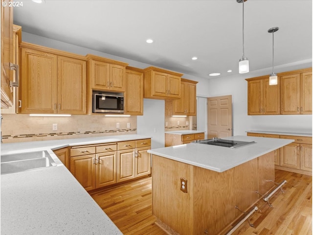 kitchen with black cooktop, backsplash, a center island, and light wood-type flooring